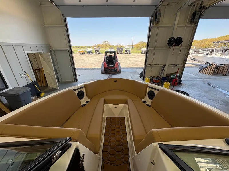 Slide: The Image of 2025 MasterCraft NXT23 boat interior with tan seating in a garage setting. - 15