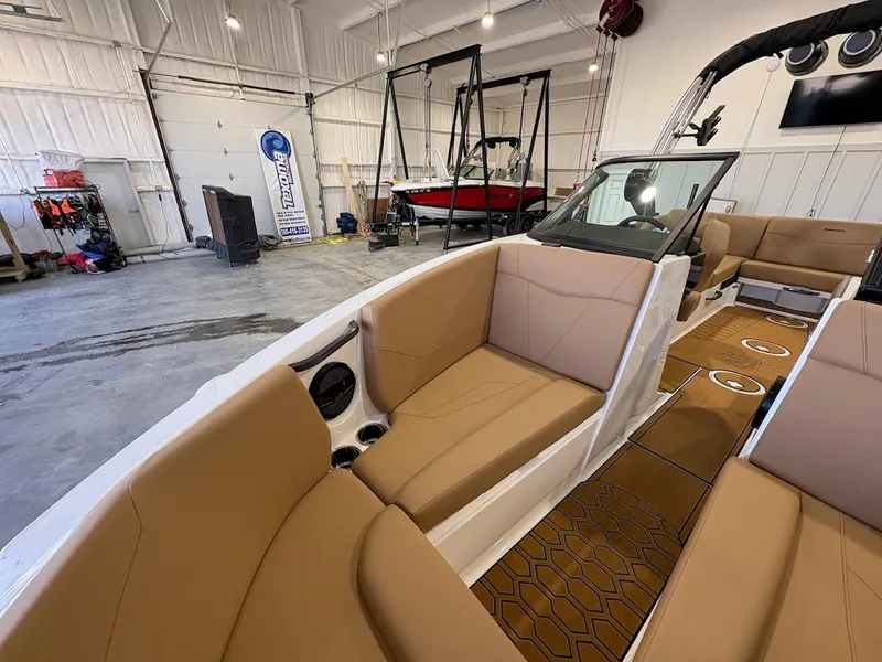 Slide: The Image of 2025 MasterCraft NXT23 boat interior with tan seating in a spacious garage. - 16