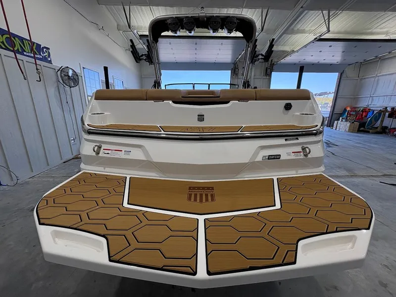 Slide: The Image of 2025 MasterCraft NXT23 boat rear view in a garage setting. - 3