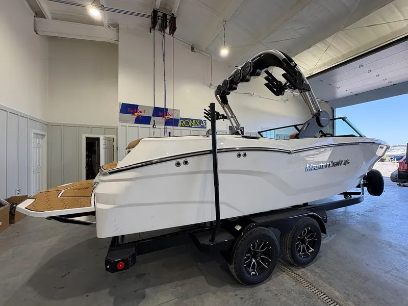 Slide: The Image of 2025 MasterCraft NXT23 boat on trailer in indoor showroom. - 4