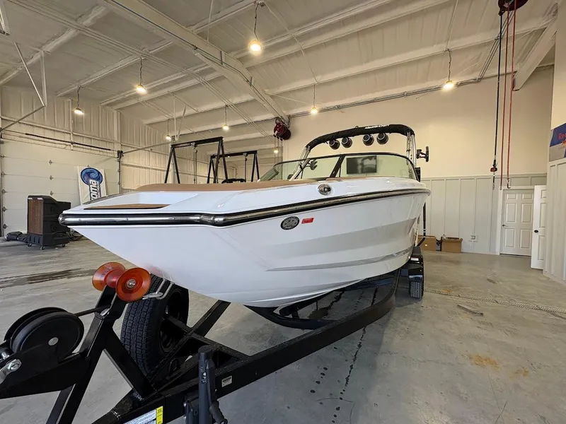 Slide: The Image of 2025 MasterCraft NXT23 boat on trailer in spacious indoor storage facility. - 7