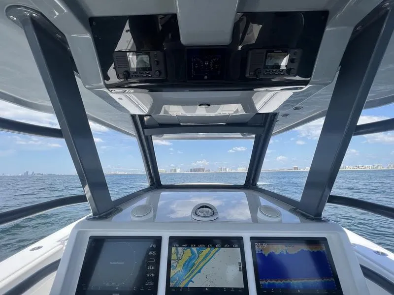 Slide: The Image of 2024 Invincible 43 Open Fisherman dashboard with navigation screens, ocean view in background. - 16
