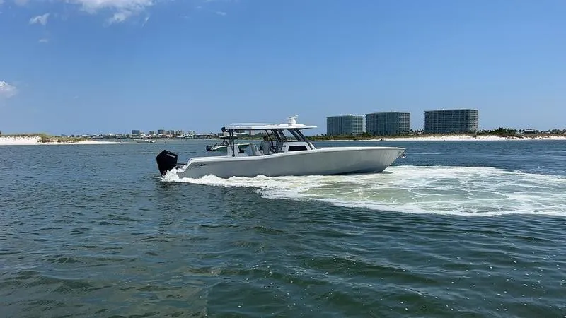 Slide: The Image of 2024 Invincible 43 Open Fisherman boat cruising on a sunny day near coastal buildings. - 6