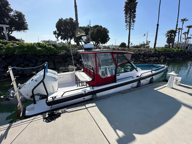 Slide: The Image of 2021 Axopar 28 Brabus T-Top boat docked in a sunny marina setting. - 3