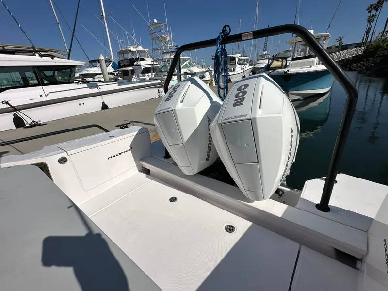 Slide: The Image of 2021 Axopar 28 Brabus T-Top with dual outboard engines docked at a marina. - 5