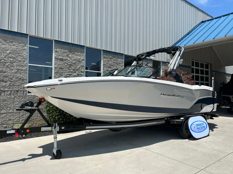 Slide: The Image of 2022 MasterCraft NXT24 boat on trailer outside a building, showcasing sleek design. - 1