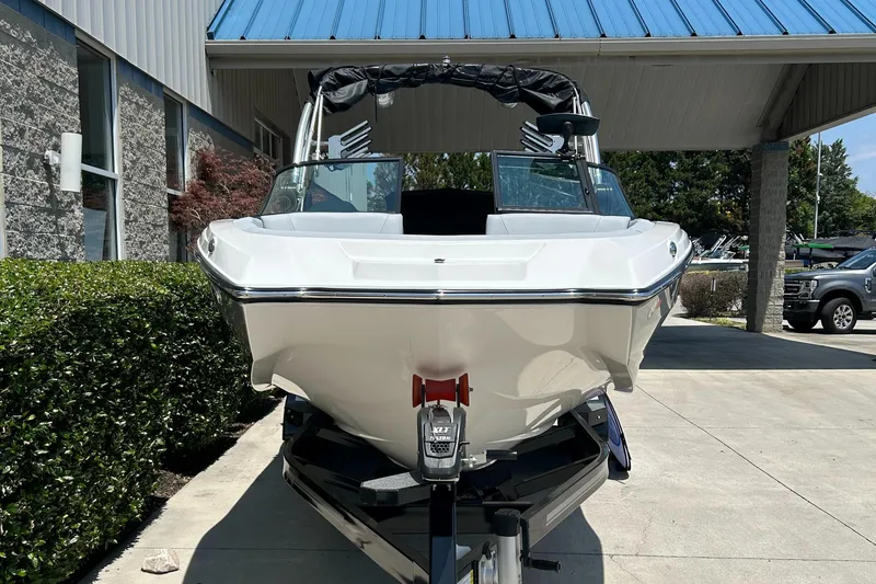 Slide: The Image of 2022 MasterCraft NXT24 boat parked outdoors, front view under a blue roof. - 3