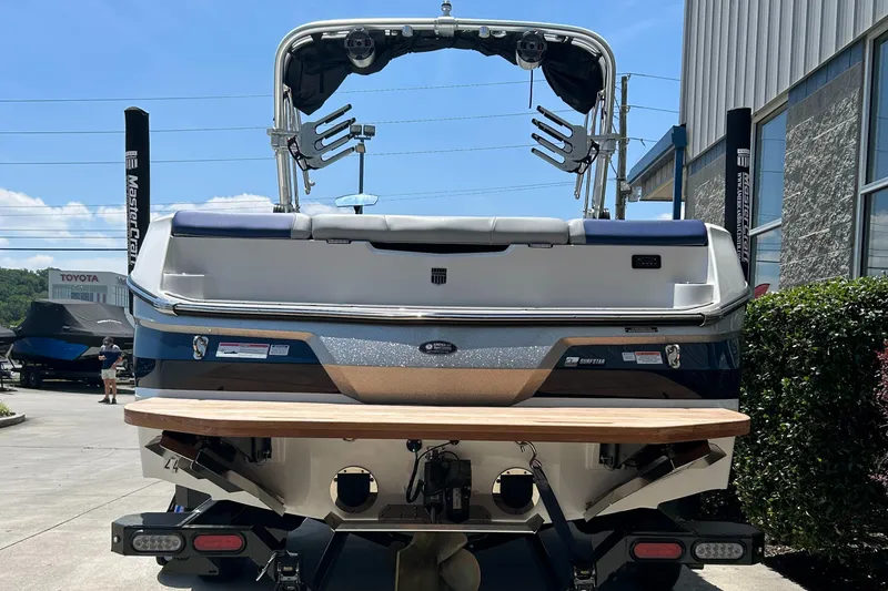 Slide: The Image of 2022 MasterCraft NXT24 boat, rear view, parked outdoors near a building. - 4