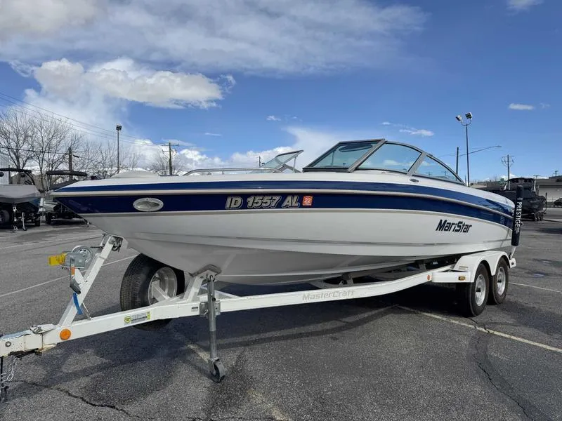Slide: The Image of 2001 MasterCraft MariStar 230 boat on trailer in parking lot under blue sky. - 2