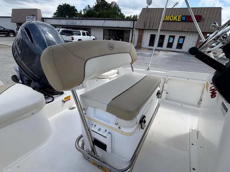 Slide: The Image of 2018 Key West 1720 Sportsman boat interior with seating and motor, parked near shops. - 20