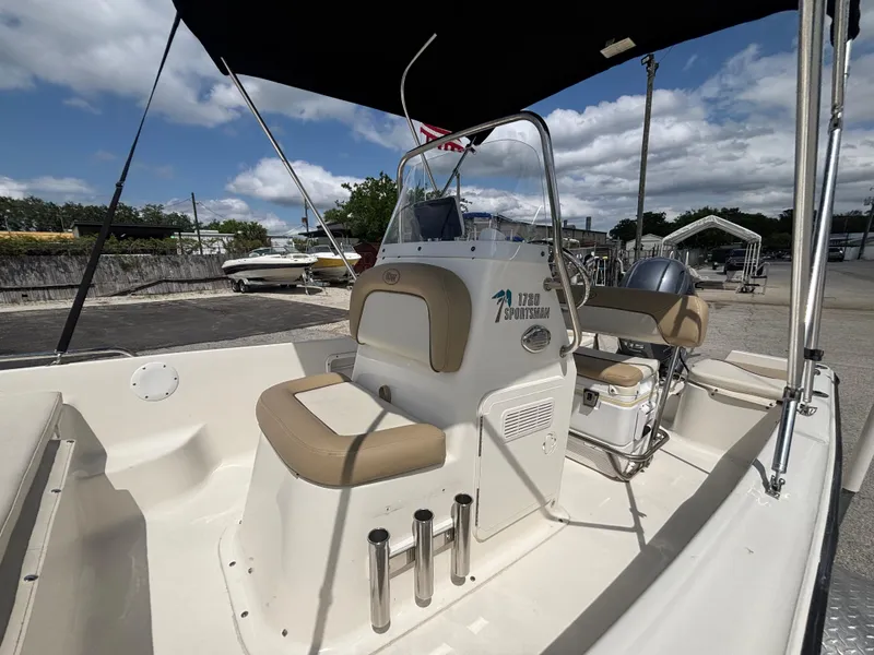 Slide: The Image of 2018 Key West 1720 Sportsman boat with beige seating and console, docked under a blue sky. - 5