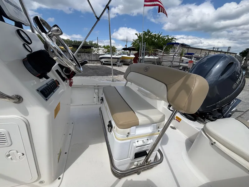 Slide: The Image of 2018 Key West 1720 Sportsman boat interior with seating and steering wheel, under a partly cloudy sky. - 9
