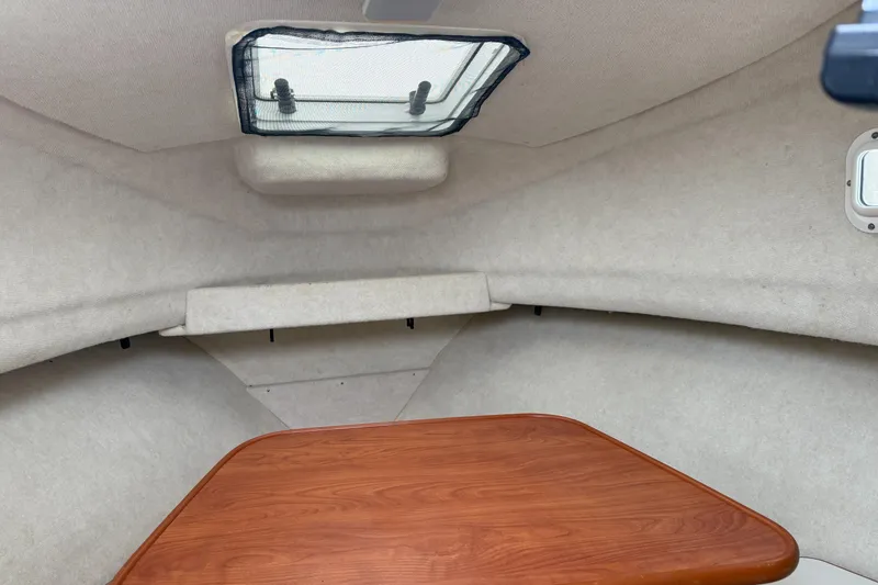 Slide: The Image of 2010 Trophy 2152 Walkaround cabin interior with wooden table and overhead hatch. - 13