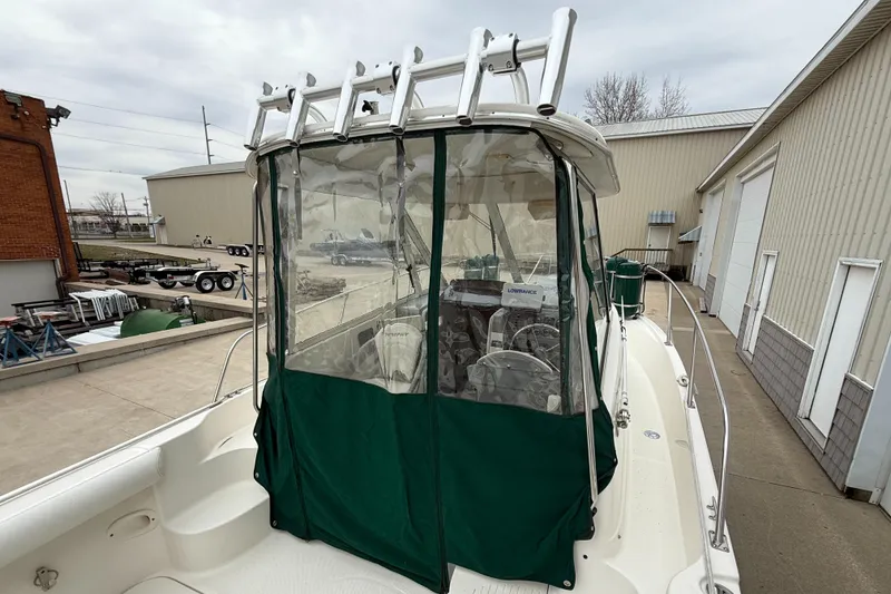 Slide: The Image of 2010 Trophy 2152 Walkaround boat with green canopy and ladder, docked near industrial buildings. - 7