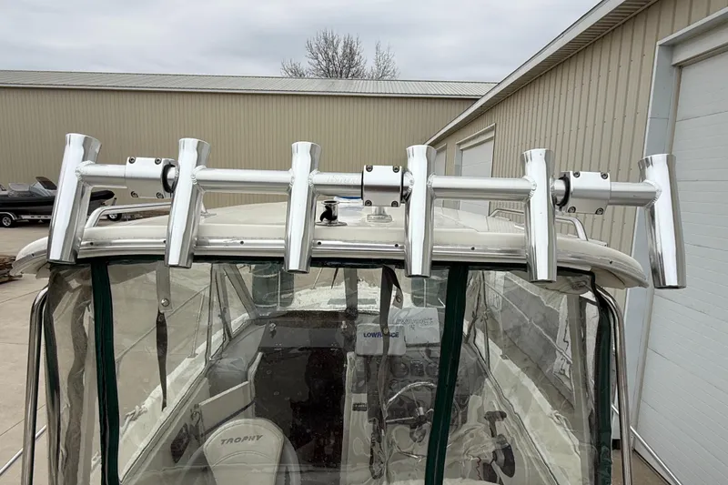 Slide: The Image of 2010 Trophy 2152 Walkaround boat with rod holders, parked near a warehouse. - 8