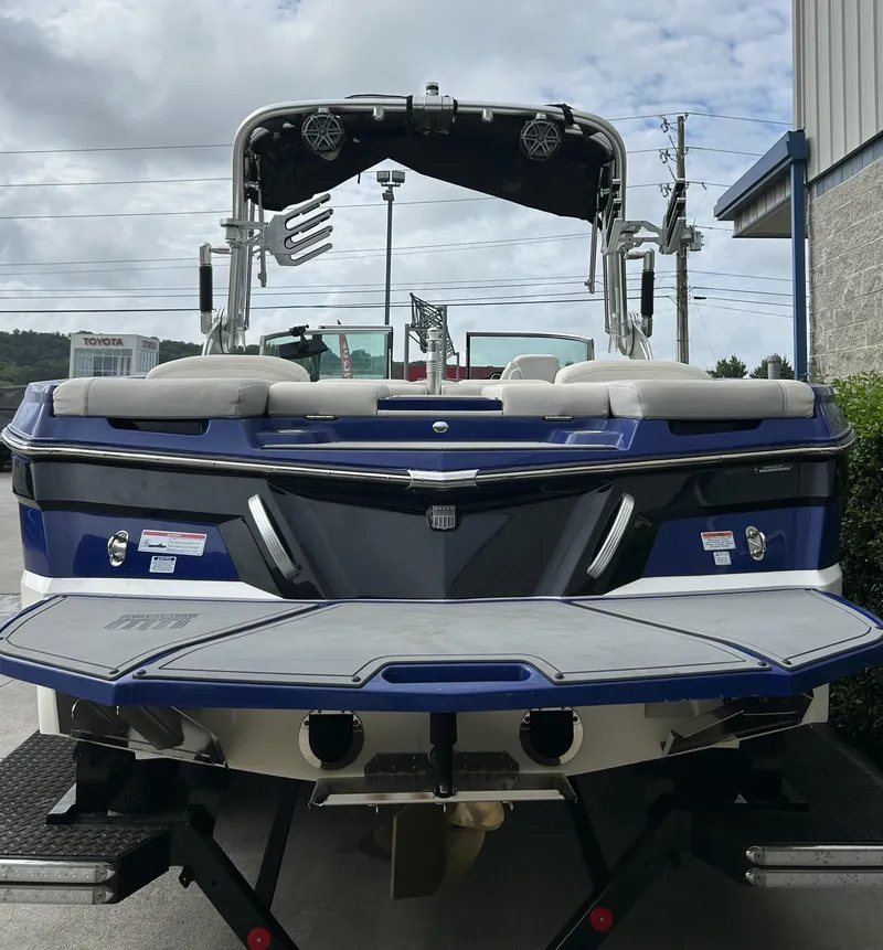 Slide: The Image of 2017 MasterCraft XT23 boat, blue and white, rear view, parked outdoors. - 3