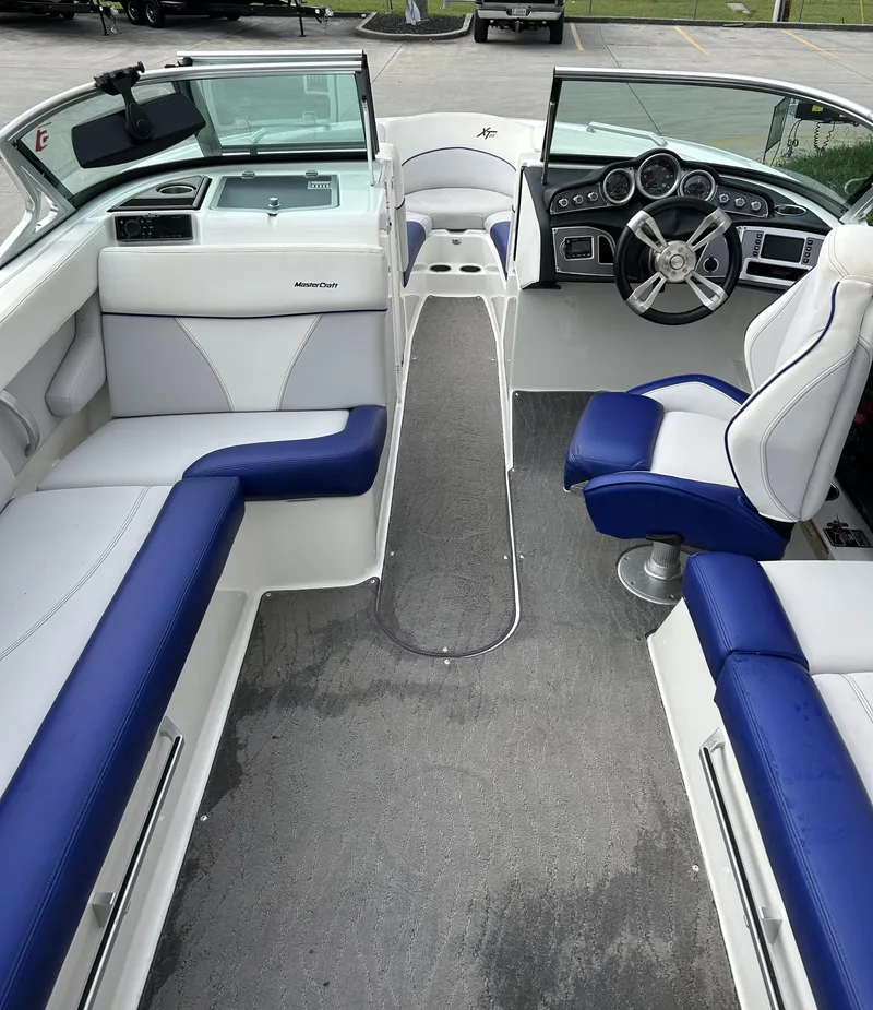 Slide: The Image of 2017 MasterCraft XT23 boat interior with blue and white seating, steering wheel, and dashboard. - 4
