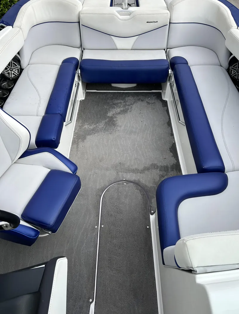 Slide: The Image of 2017 MasterCraft XT23 boat interior with blue and white seating, spacious layout. - 7