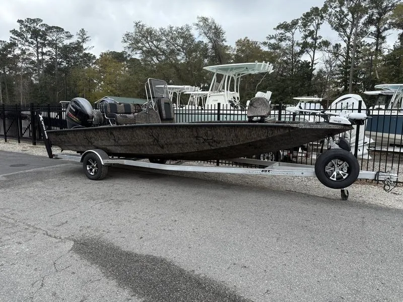Slide: The Image of 2025 Xpress H22B Bay boat on trailer, parked outdoors near other boats. - 0