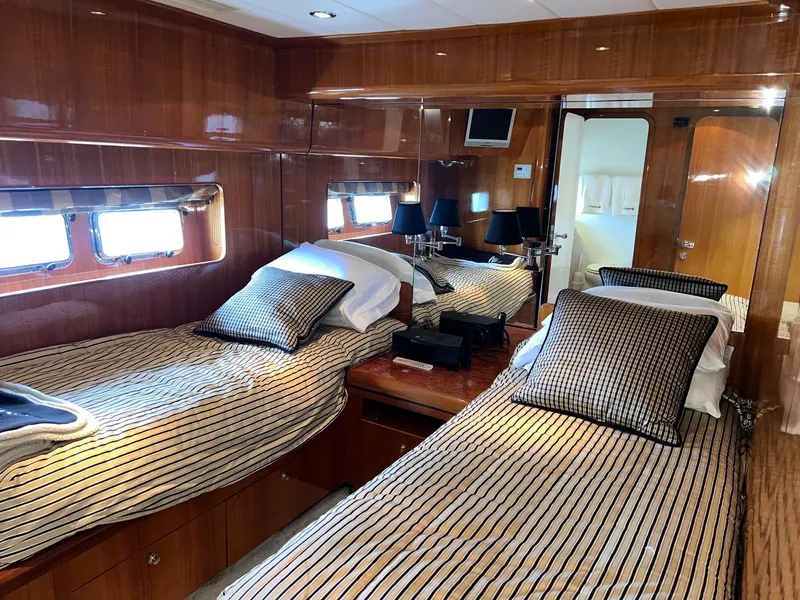 Slide: The Image of Luxurious twin cabin in 2001 Horizon Skylounge yacht with wood paneling and striped bedding. - 33