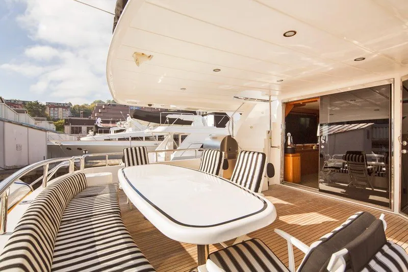 Slide: The Image of Luxurious 2001 Horizon Skylounge yacht deck with striped seating and elegant dining area. - 4