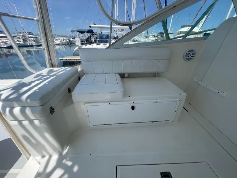 Slide: The Image of 1997 Cabo 31 Express boat interior with white seating and storage, docked at a marina. - 17