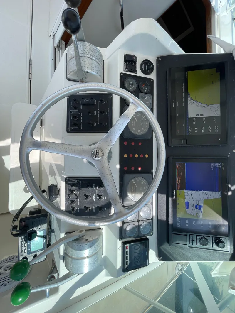 Slide: The Image of 1997 Cabo 31 Express helm with steering wheel, gauges, and navigation screens. - 19