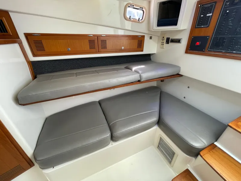 Slide: The Image of 1997 Cabo 31 Express cabin interior with gray seating and wooden accents. - 28