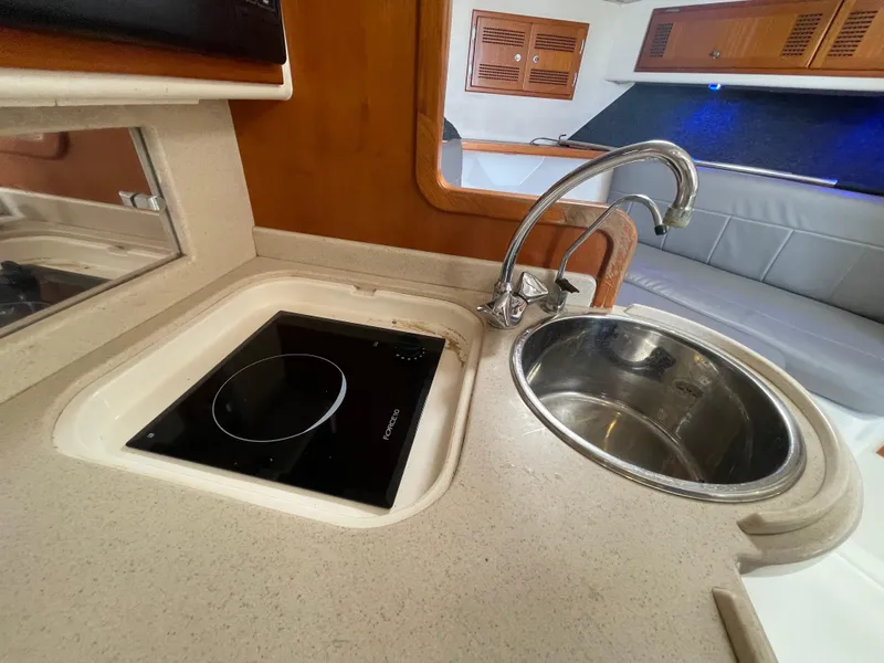 Slide: The Image of Compact kitchen area in a 1997 Cabo 31 Express boat with sink and stove. - 30