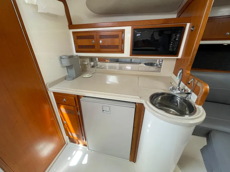 Slide: The Image of 1997 Cabo 31 Express boat kitchen with sink, microwave, and wooden cabinetry. - 31