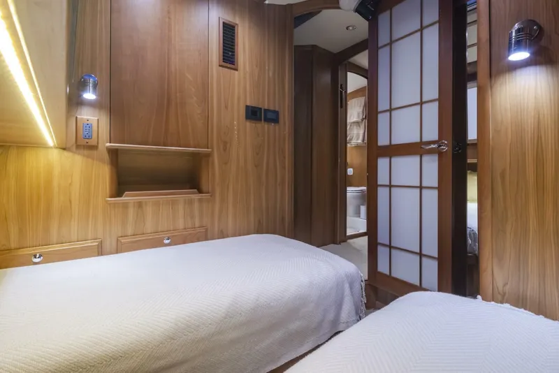 Slide: The Image of 2018 Sabre 45 Salon Express interior with twin beds, wooden paneling, and soft lighting. - 16