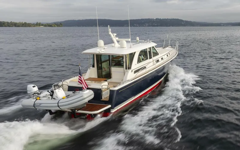 Slide: The Image of 2018 Sabre 45 Salon Express yacht cruising on open water with inflatable boat attached. - 4