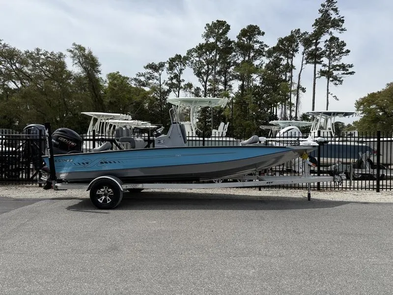Slide: The Image of 2025 Xpress H20B boat on trailer, parked outdoors near trees and other boats. - 1