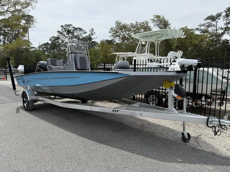 Slide: The Image of 2025 Xpress H20B boat on trailer, blue and gray, parked outdoors. - 2
