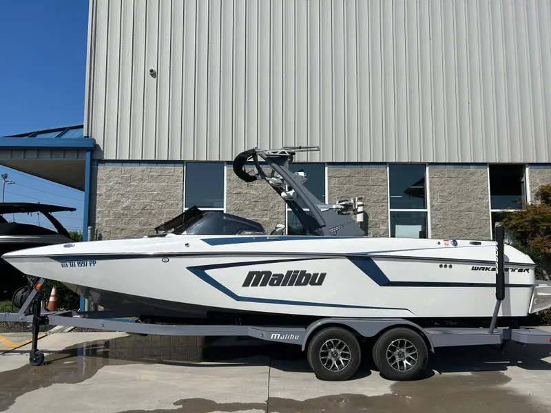 Slide: The Image of 2021 Malibu Wakesetter 24 MXZ boat on trailer, parked outside a building. - 0
