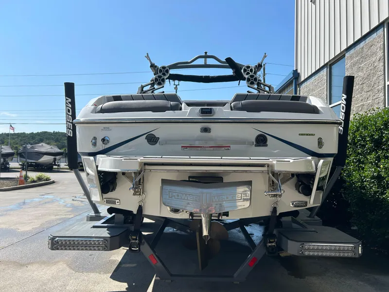 Slide: The Image of 2021 Malibu Wakesetter 24 MXZ boat, rear view, parked outdoors near a building. - 2
