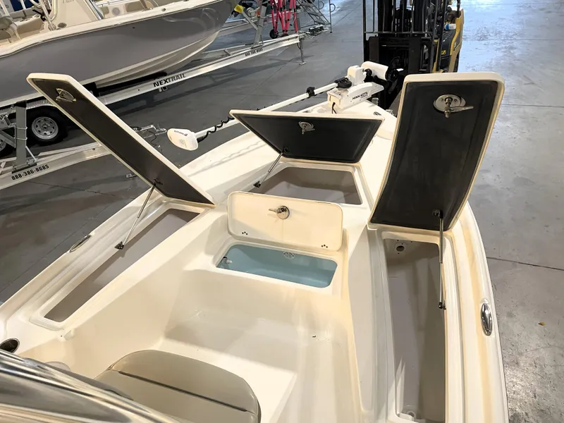 Slide: The Image of 2024 Key West 210 Bay Reef boat with open storage compartments in a showroom. - 23