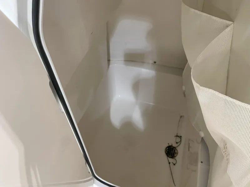 Slide: The Image of 2024 Key West 210 Bay Reef interior storage compartment with white finish and curtain. - 27