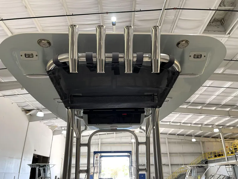 Slide: The Image of 2024 Key West 210 Bay Reef boat T-top with rod holders in a warehouse. - 40