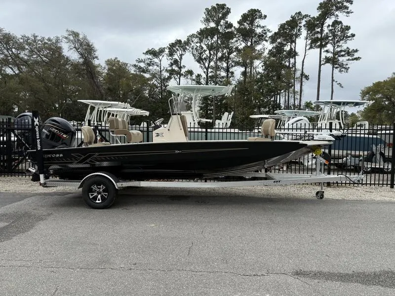 Slide: The Image of 2025 Xpress H20B boat on trailer, parked outdoors with trees in background. - 1