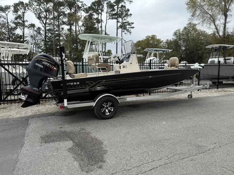 Slide: The Image of 2025 Xpress H20B boat on trailer with Yamaha outboard motor, parked near other boats. - 2