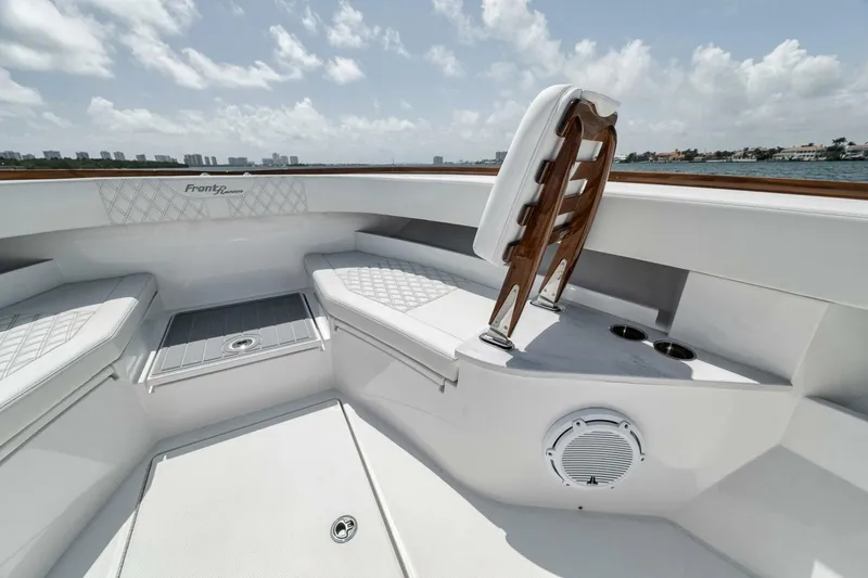 Slide: The Image of 2024 Front Runner 47 Center Console boat interior with seating and speaker, under clear skies. - 20