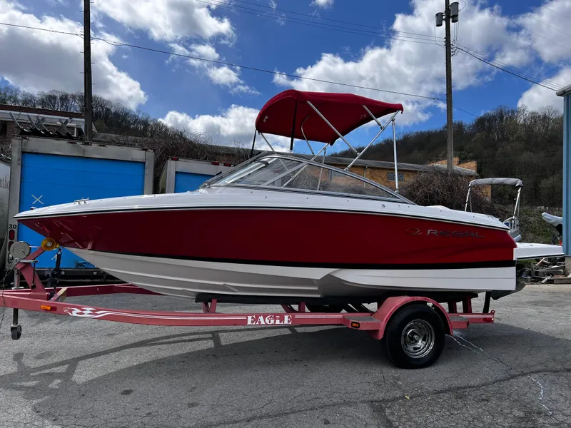 Slide: The Image of Red 2006 Regal 1900 Bowrider boat on trailer, parked outdoors under cloudy sky. - 1