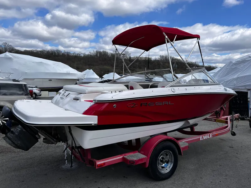 Slide: The Image of 2006 Regal 1900 Bowrider boat with red canopy on a trailer, parked outdoors. - 3