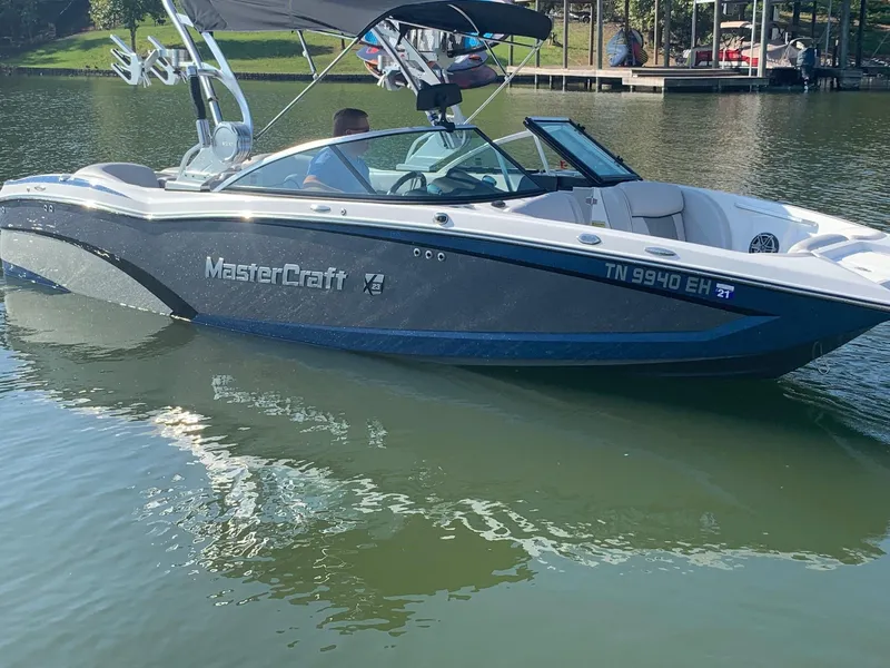 Slide: The Image of 2015 MasterCraft X23 boat on a calm lake, featuring sleek design and modern amenities. - 0