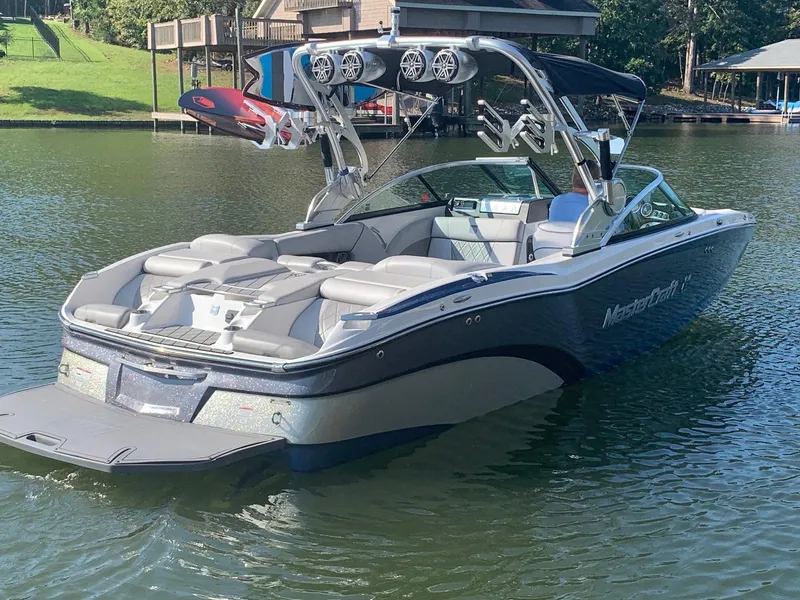 Slide: The Image of 2015 MasterCraft X23 boat on a lake, featuring sleek design and wakeboard tower. - 1