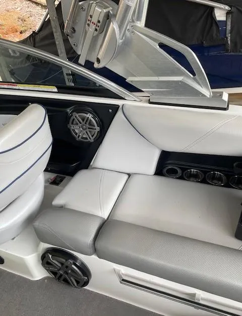 Slide: The Image of 2015 MasterCraft X23 boat interior with white and gray seating, cup holders, and speakers. - 17