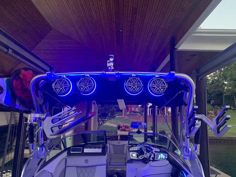 Slide: The Image of 2015 MasterCraft X23 boat with illuminated speakers and wakeboard racks under a wooden canopy. - 23