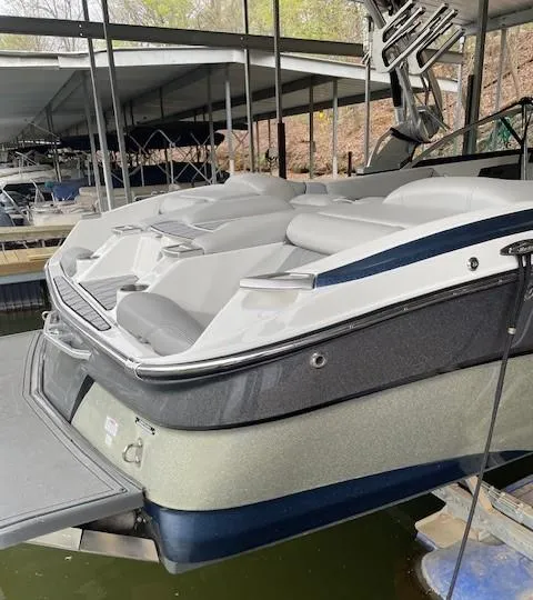 Slide: The Image of 2015 MasterCraft X23 boat docked in a marina, showcasing sleek design and seating area. - 5