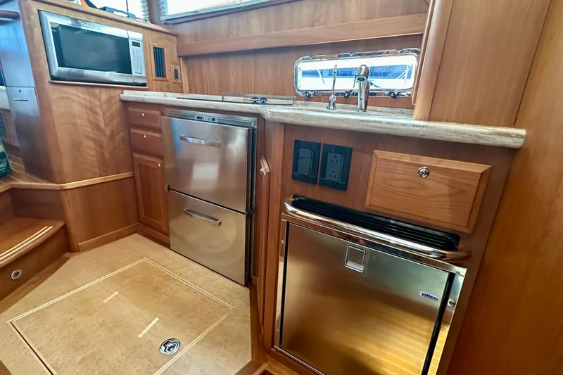 Slide: The Image of 2017 Sabre 42 Salon Express galley with stainless steel appliances and wood cabinetry. - 12